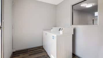 A laundry room with a washing machine, a door, and a wooden floor.