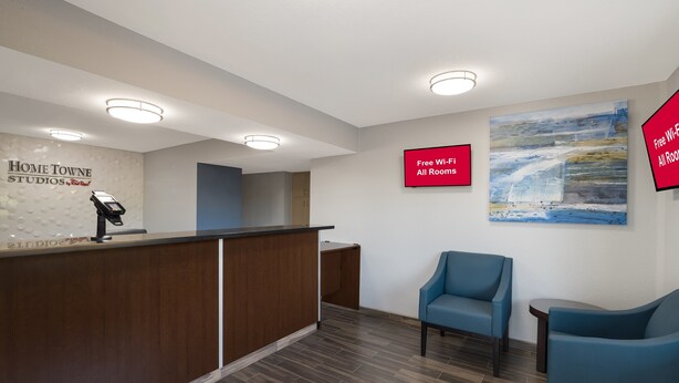 A reception area with a wooden desk, a blue chair, and a painting on the wall.