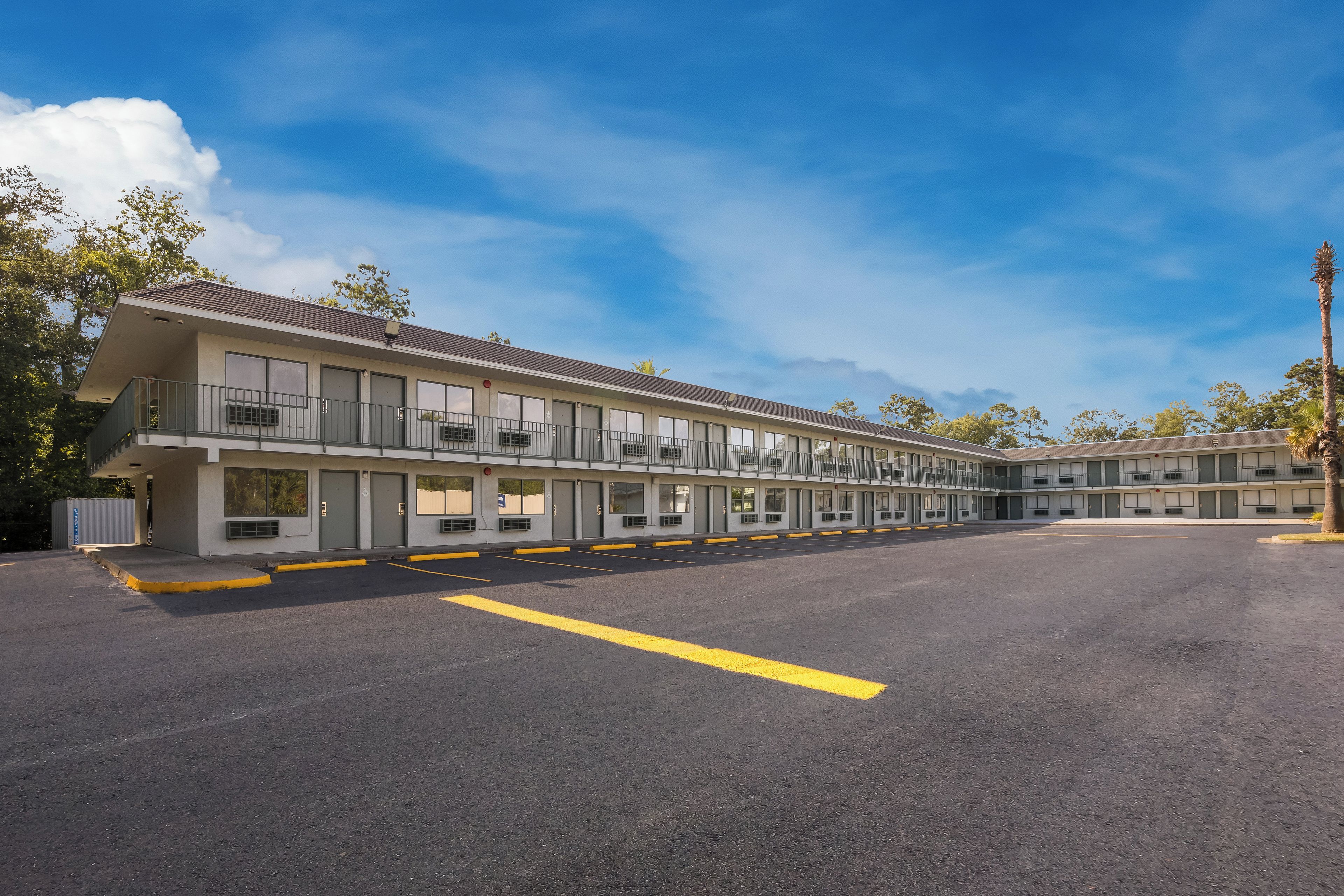 A motel with multiple rooms, a parking lot, and a clear sky.
