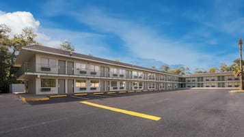 A motel with multiple rooms, a parking lot, and a clear sky.