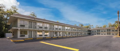 A motel with multiple rooms, a parking lot, and a clear sky.