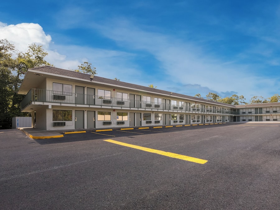 A motel with multiple rooms, a parking lot, and a clear sky.