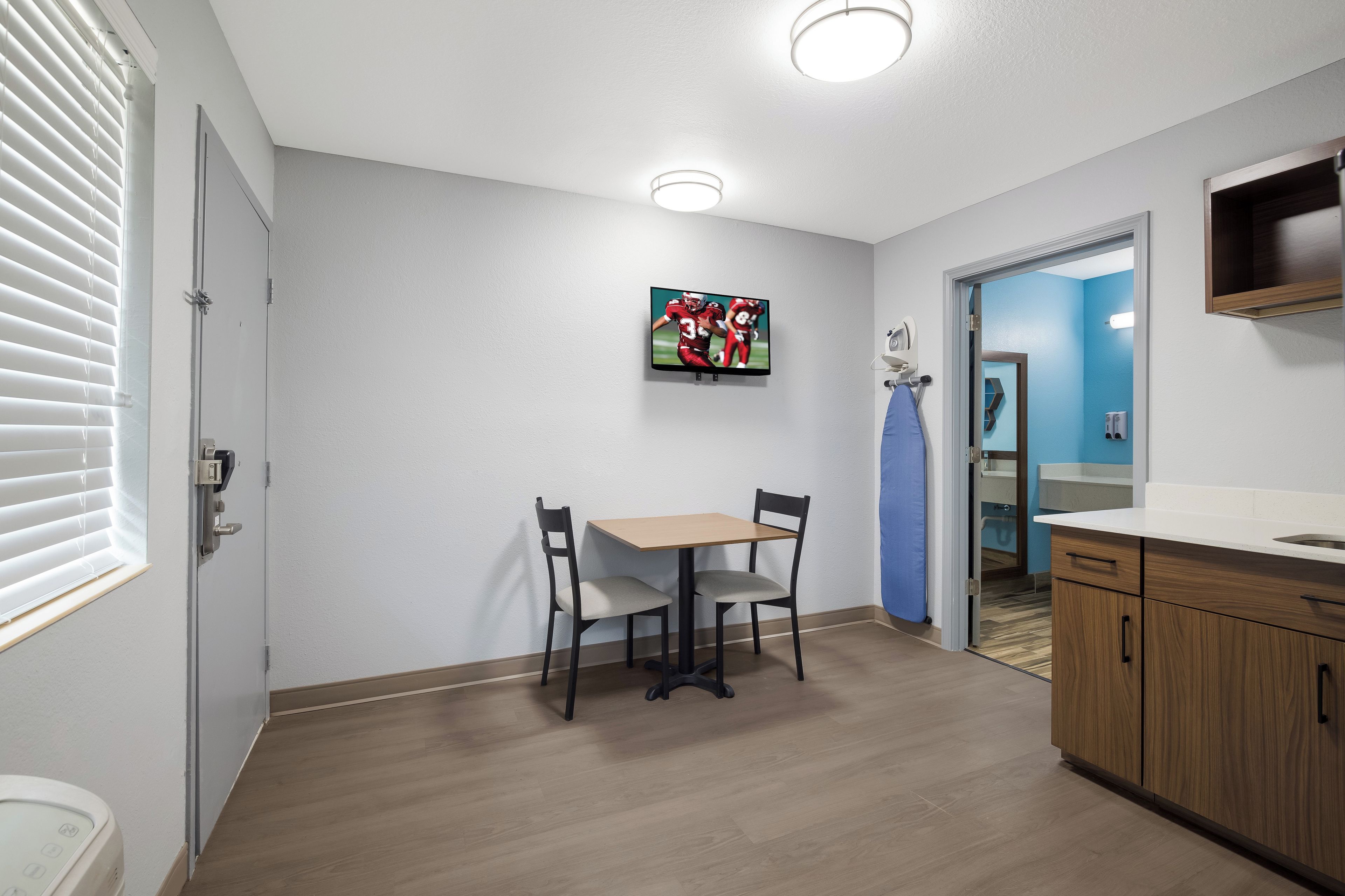 Una cocina moderna con armarios de madera, una encimera y un televisor instalado en la pared.