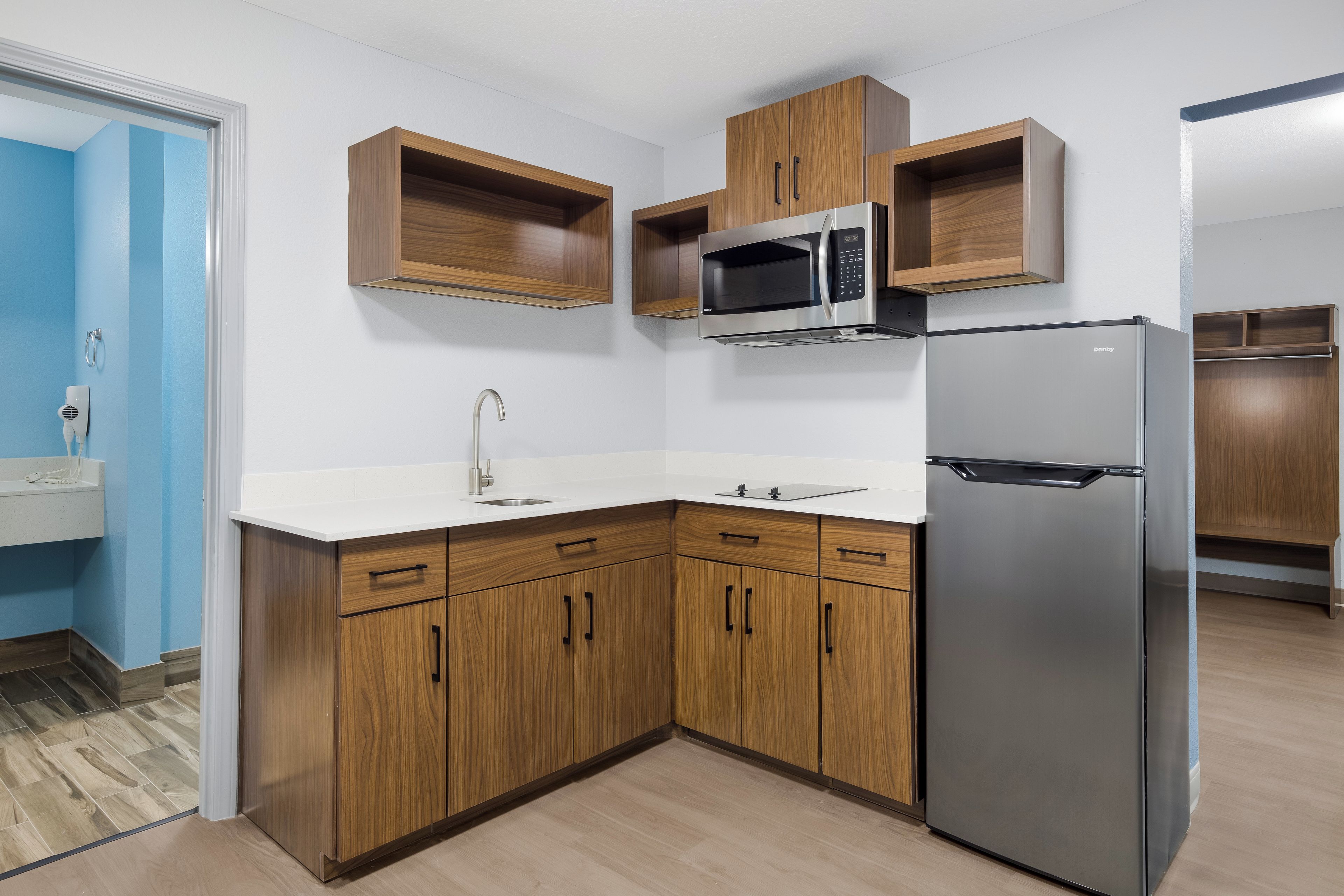 Eine Küche mit Holzschränken, einem Edelstahlkühlschrank und einer Mikrowelle.