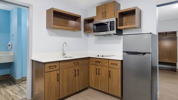Eine Küche mit Holzschränken, einem Edelstahlkühlschrank und einer Mikrowelle.