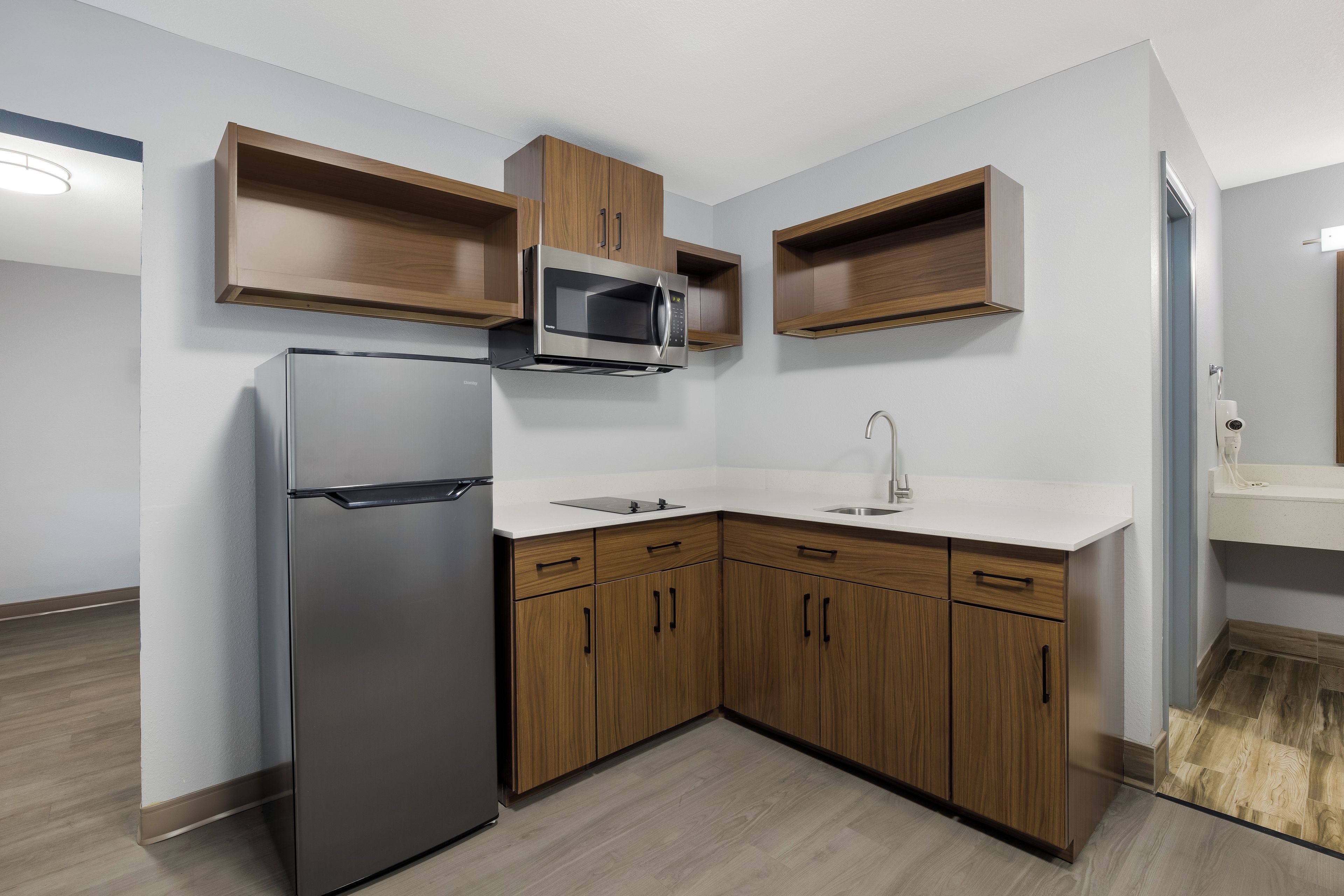 Een moderne keuken met een ingebouwde magnetron, koelkast en houten kastjes.