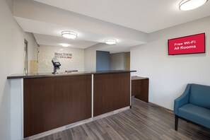 A reception desk with a digital payment terminal, a sign indicating free Wi-Fi, and a blue seating area.