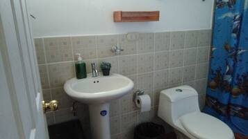 Un baño con lavamanos, inodoro y un pequeño cubo de basura.