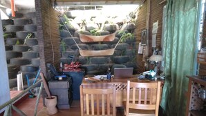Un interior rústico con una mesa de madera, dos sillas, una computadora portátil y una pared decorada con neumáticos y plantas.