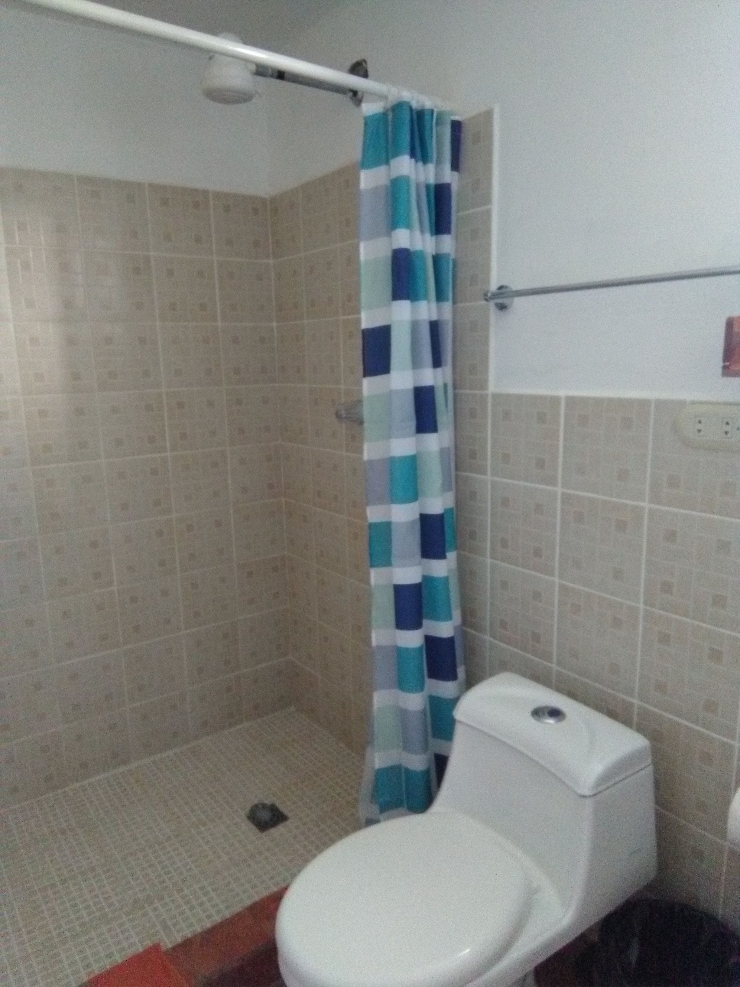 A bathroom with a shower, toilet, and tiled walls.