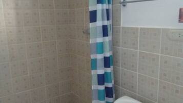 Un baño con ducha, inodoro y paredes de azulejos.