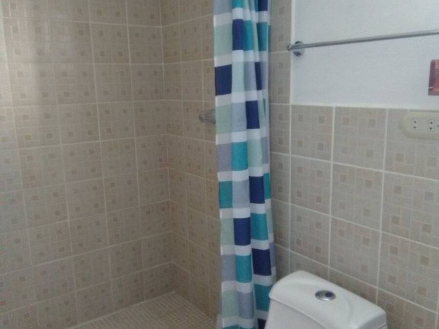 Un baño con ducha, inodoro y paredes de azulejos.