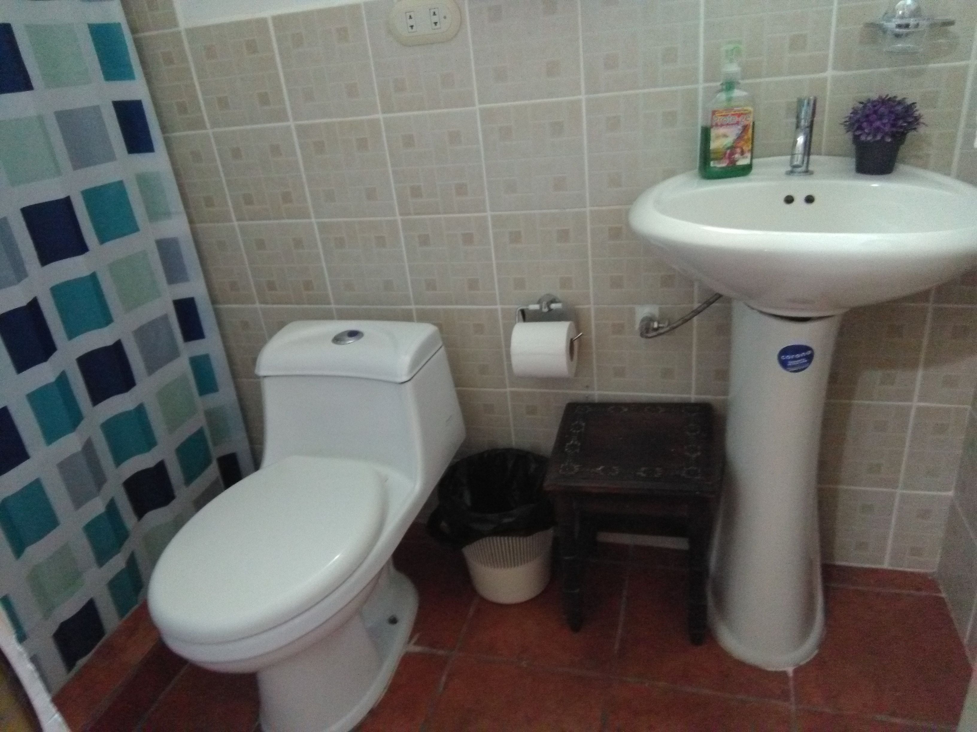 Une salle de bain avec des toilettes, un lavabo et des murs carrelés.