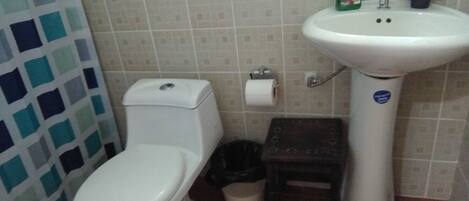 Une salle de bain avec des toilettes, un lavabo et des murs carrelés.