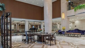 A spacious lobby with a central coffee table, seating area, and a large pillar. - Xihai Ecological Garden Vacation Hotel Liu’an (Lu'an)
