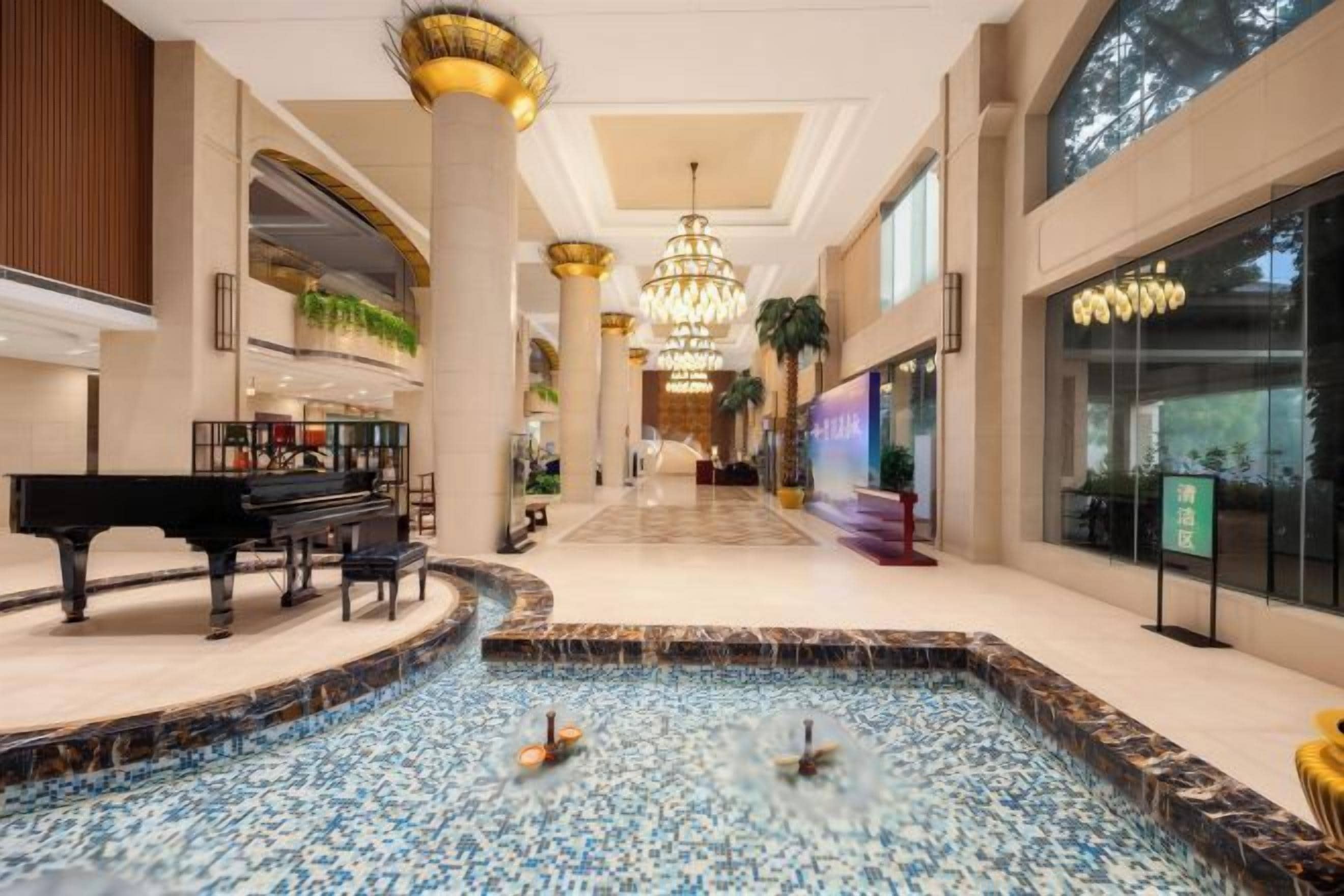 A spacious lobby with a grand piano, a fountain, and a chandelier.
