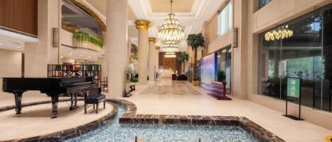A spacious lobby with a grand piano, a fountain, and a chandelier.