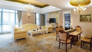 A spacious living room with a large sofa, a coffee table, and a dining area with chairs and a table. - Xihai Ecological Garden Vacation Hotel Liu’an (Lu'an)