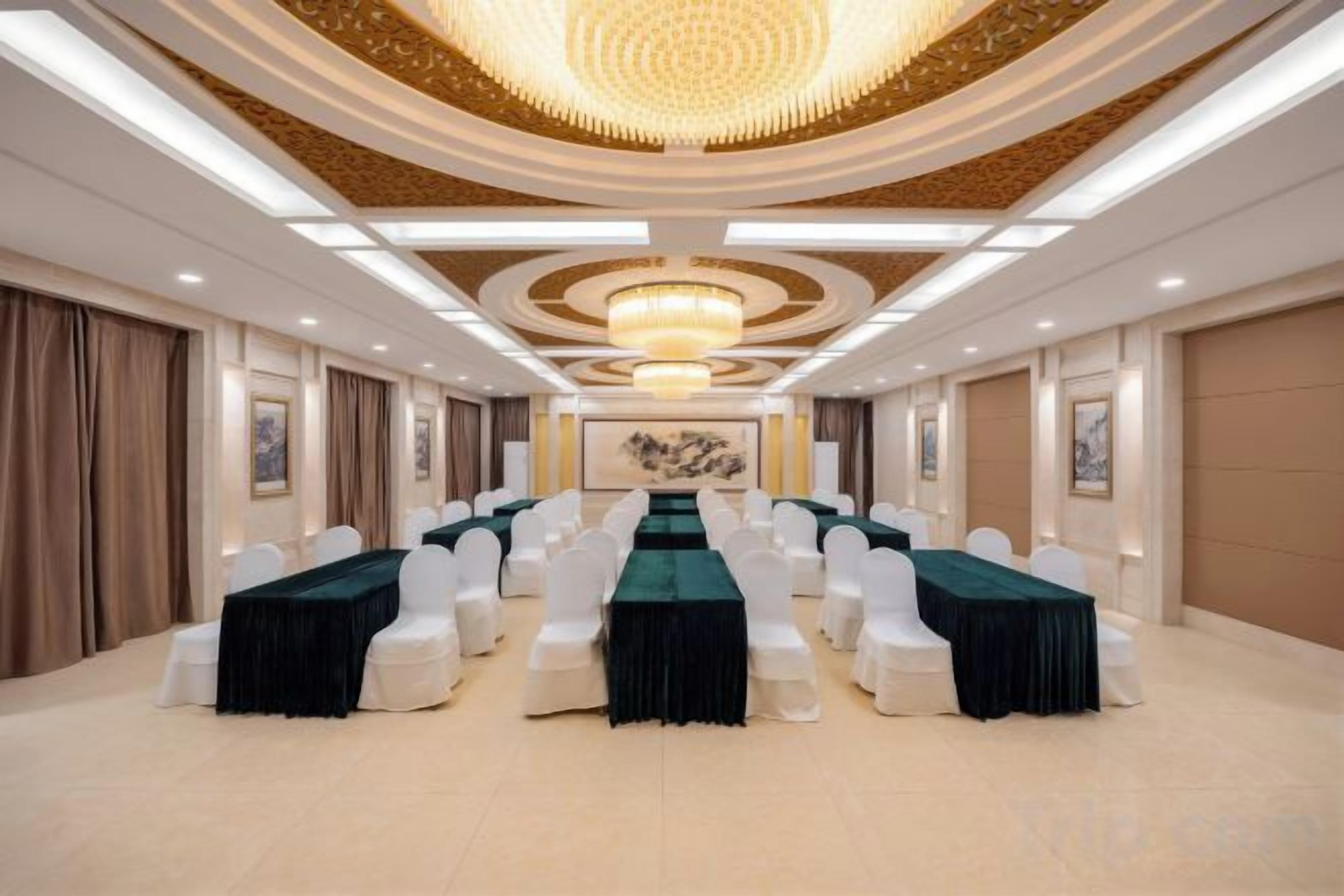 A conference room with a long table, white chairs, and a chandelier.