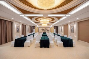 A conference room with a long table, white chairs, and a chandelier.