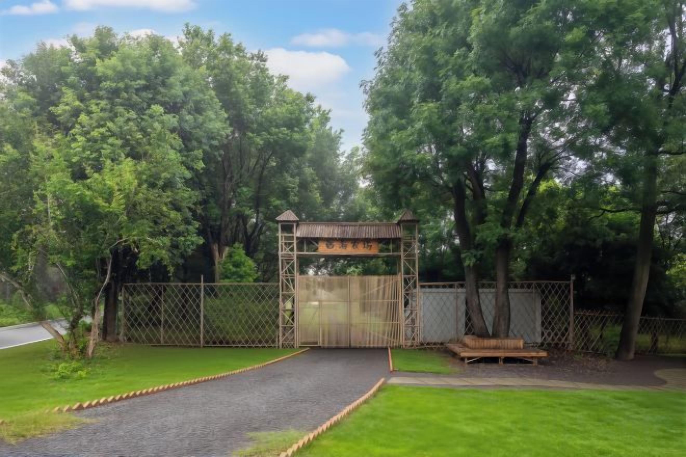A gated entrance to a park with a paved path leading to a wooden bench.