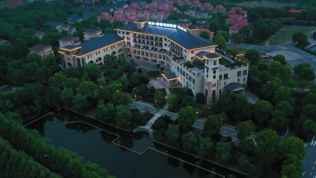 An aerial view of a large, multi-story hotel with a central courtyard and surrounding greenery. - Xihai Ecological Garden Vacation Hotel Liu’an (Lu'an)