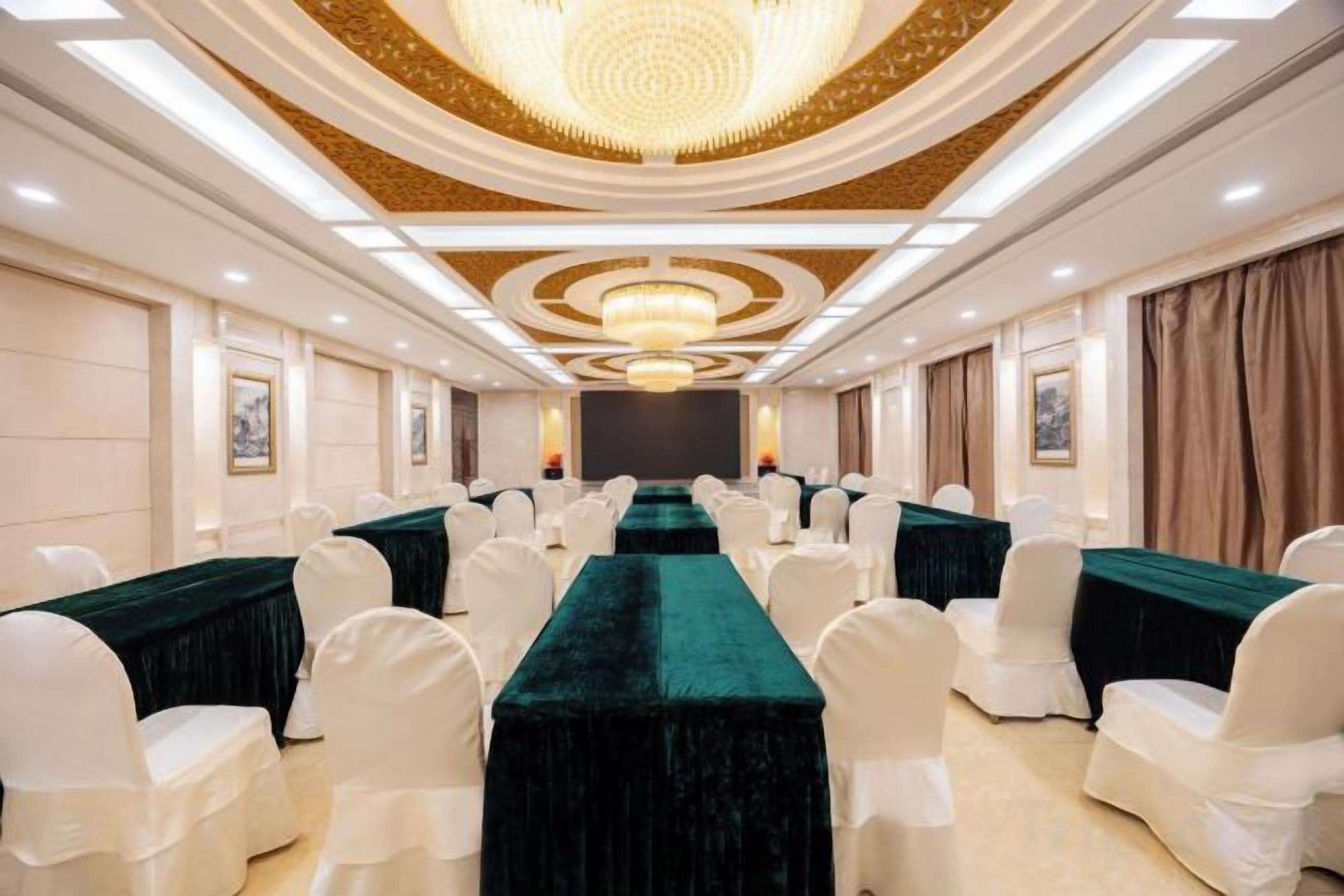 A conference room with a long table, white chairs, and a chandelier.
