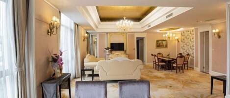 A hotel lobby with a sofa, dining table, chairs, a chandelier, and wall sconces.