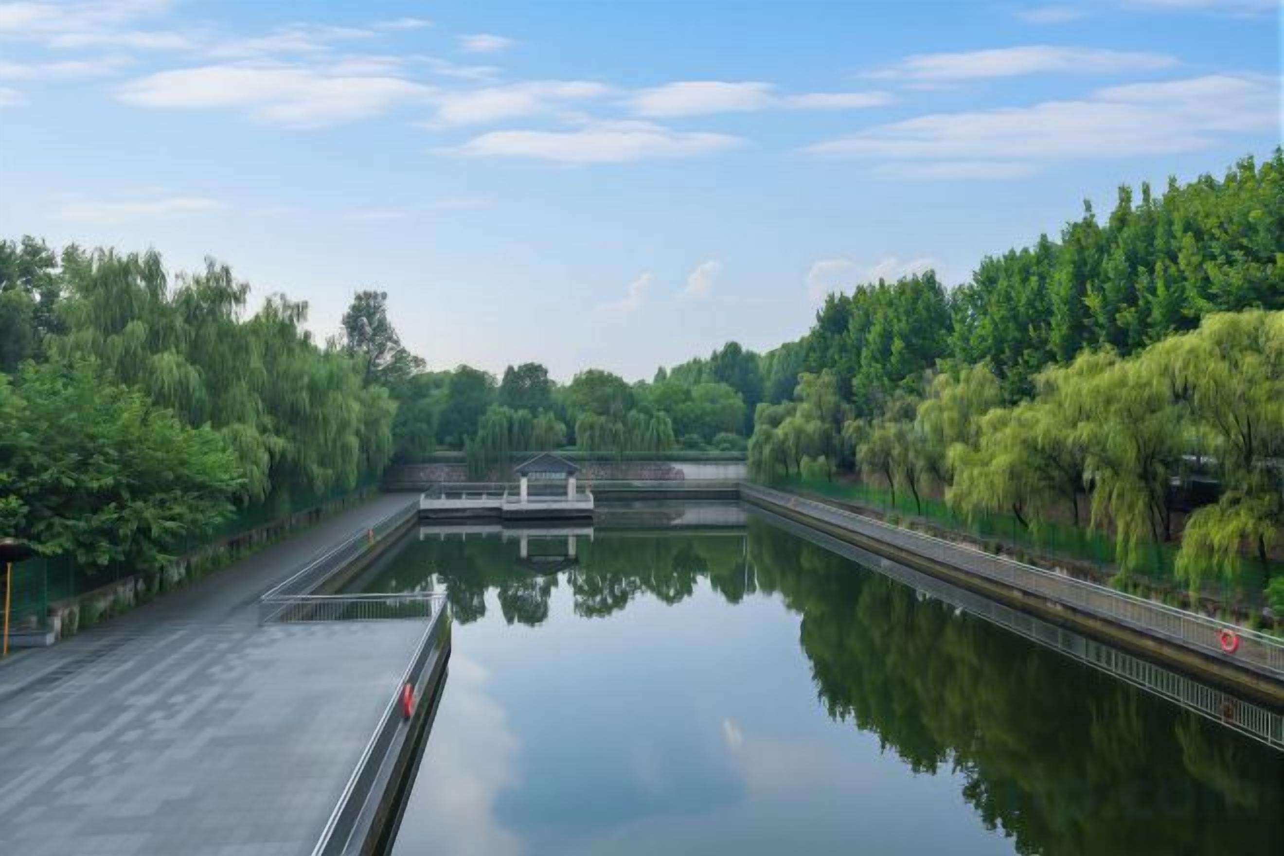 A calm water body with a bridge, surrounded by lush greenery.
