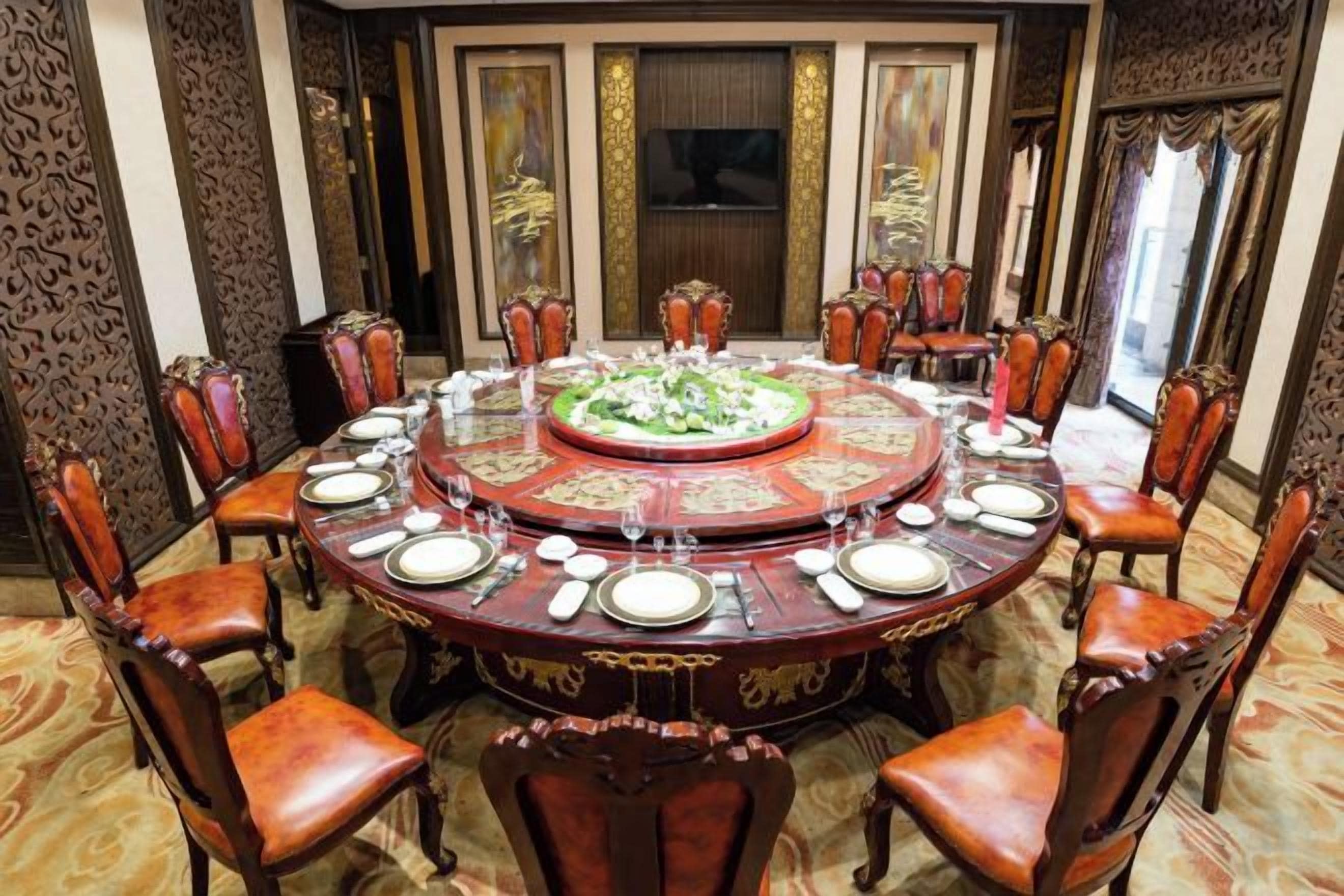 Una mesa redonda de comedor con sillas, rodeada de paneles ornamentales en la pared y un espejo grande.
