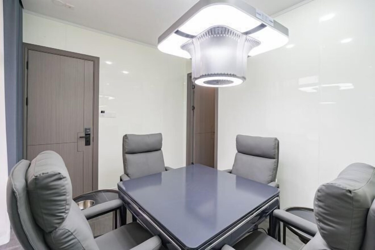 A conference room with a rectangular table, four grey chairs, and a modern pendant light fixture.