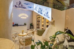 A modern interior with a reception desk, seating area, and decorative elements including a mannequin in a dress and bird sculptures. - Xihai Ecological Garden Vacation Hotel Liu’an (Lu'an)