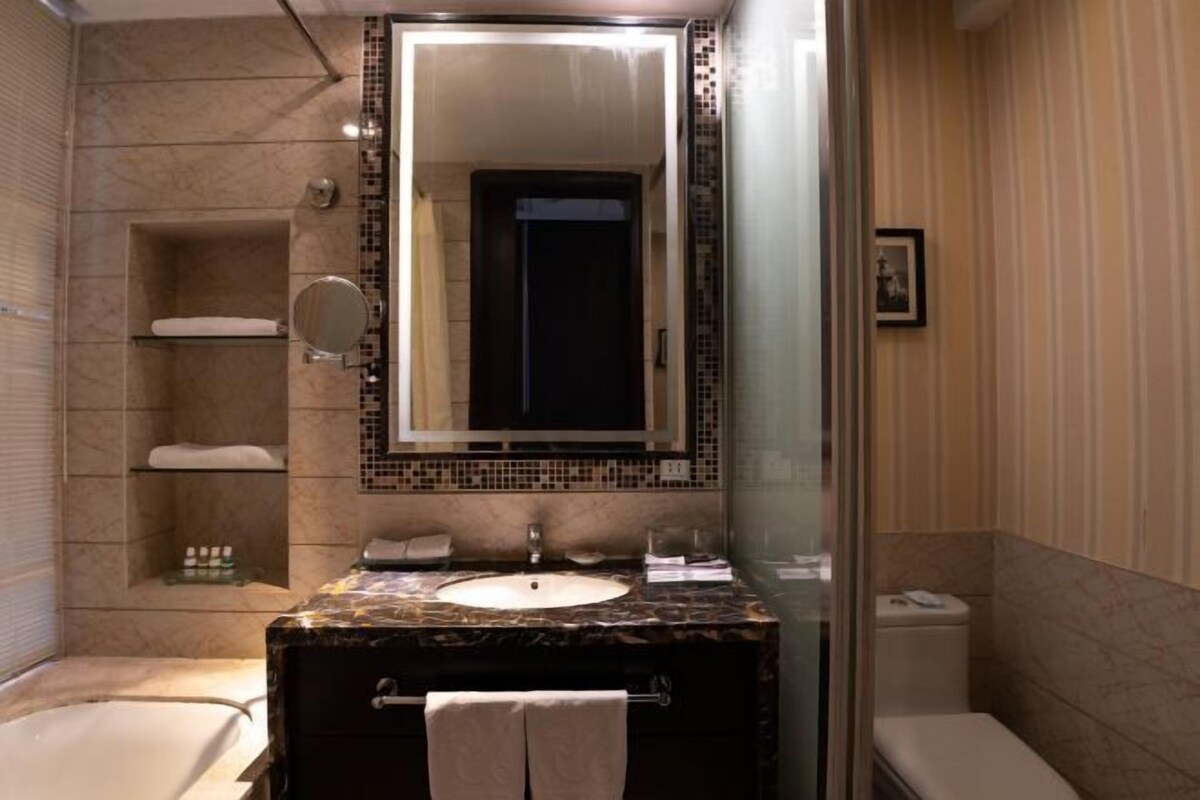 A bathroom with a marble sink, a glass-enclosed shower, and a toilet.