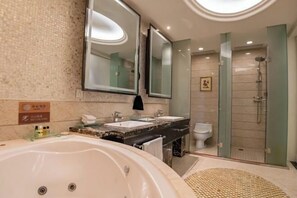 A modern bathroom with a large bathtub, two sinks, a glass shower enclosure, and a mirror.
