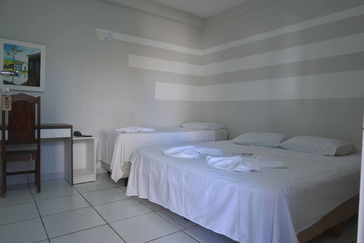 A bedroom with two beds, a desk, and a chair.