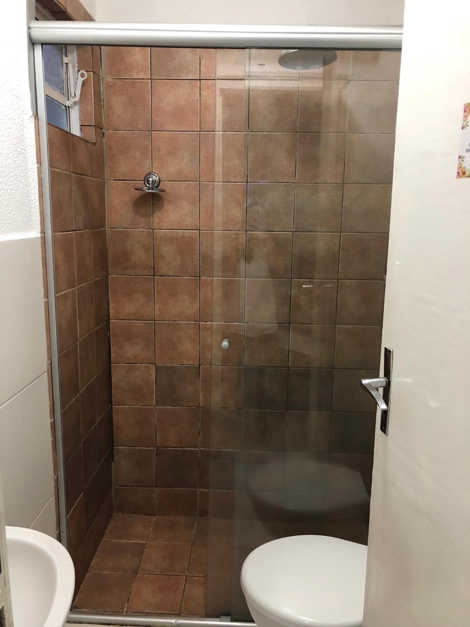 Un baño pequeño con ducha, inodoro y lavamanos.