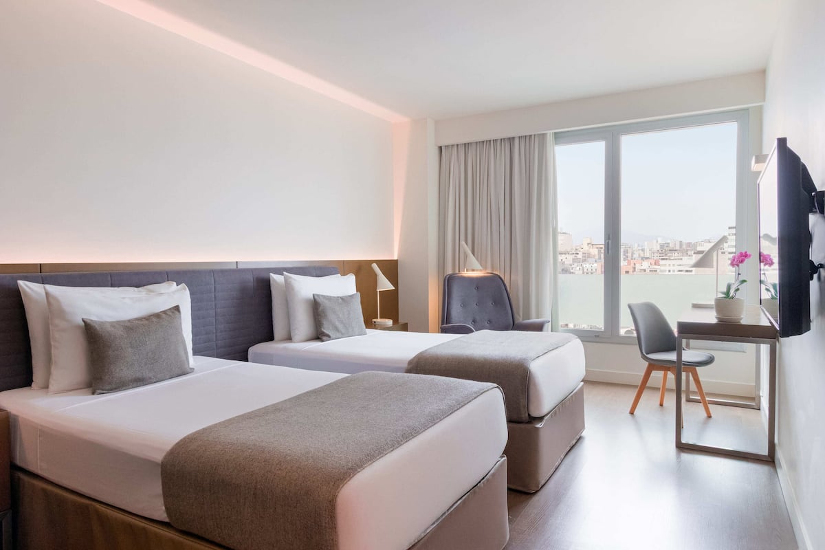 Ein Hotelzimmer mit zwei Betten, einem Schreibtisch und einem Stuhl.