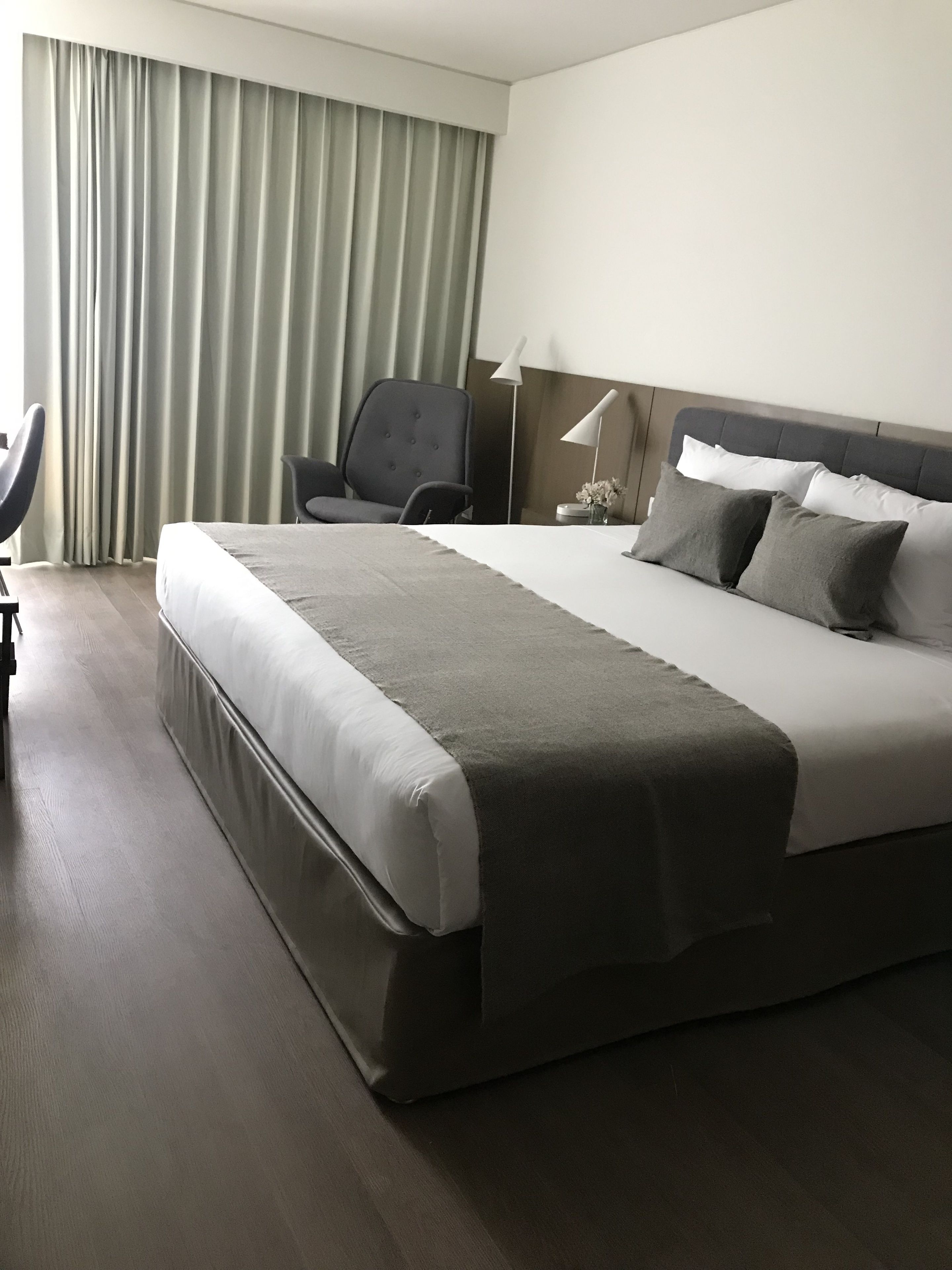 Une chambre d’hôtel moderne avec un grand lit, une chaise, un bureau et une lampe.