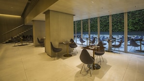 Un espace de restauration moderne, avec des tables et des chaises, de grandes fenêtres et un escalier.