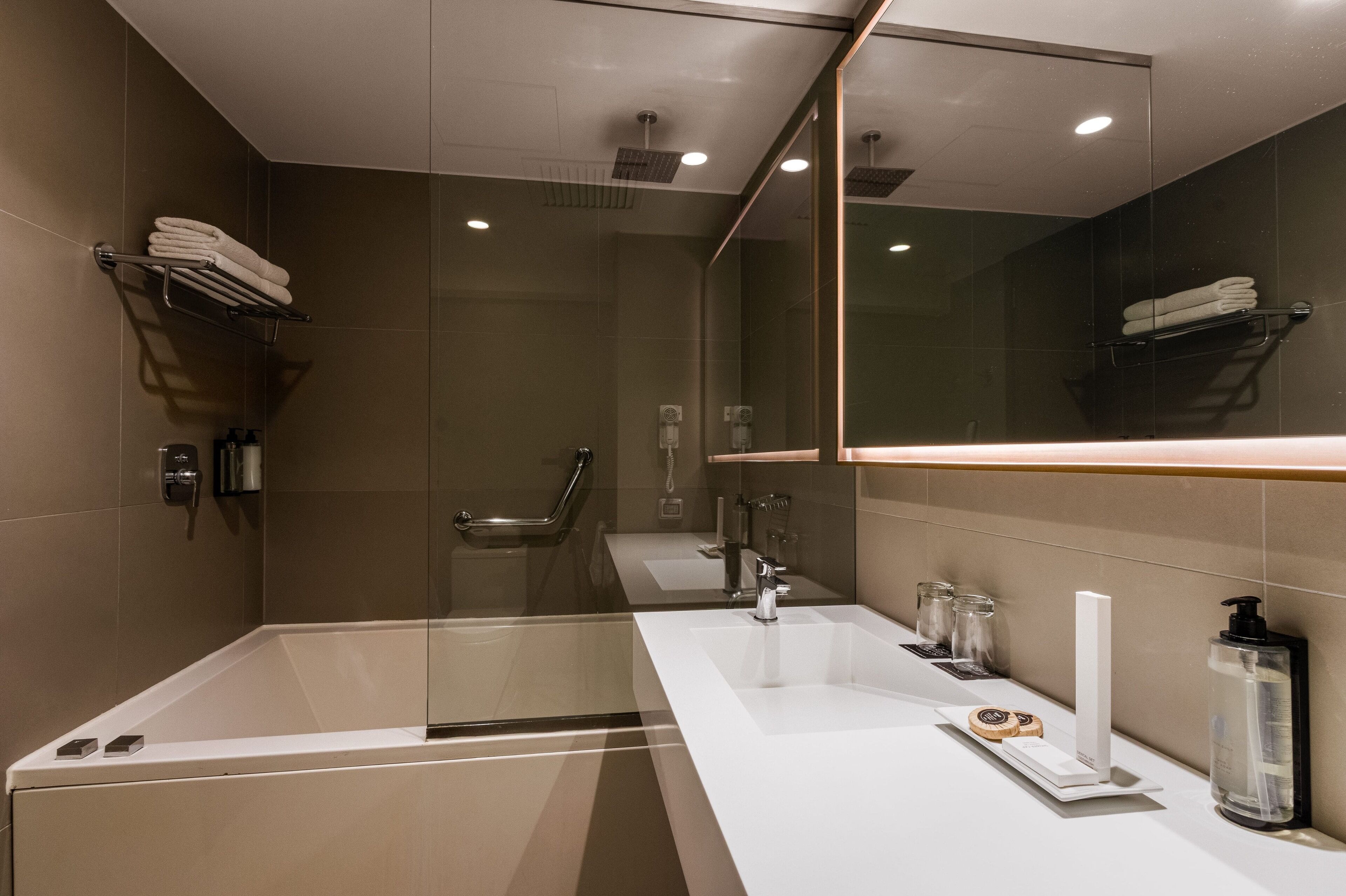 Un bagno moderno con doccia vetrata, una vasca da bagno ampia e un mobile vanitario con specchio.
