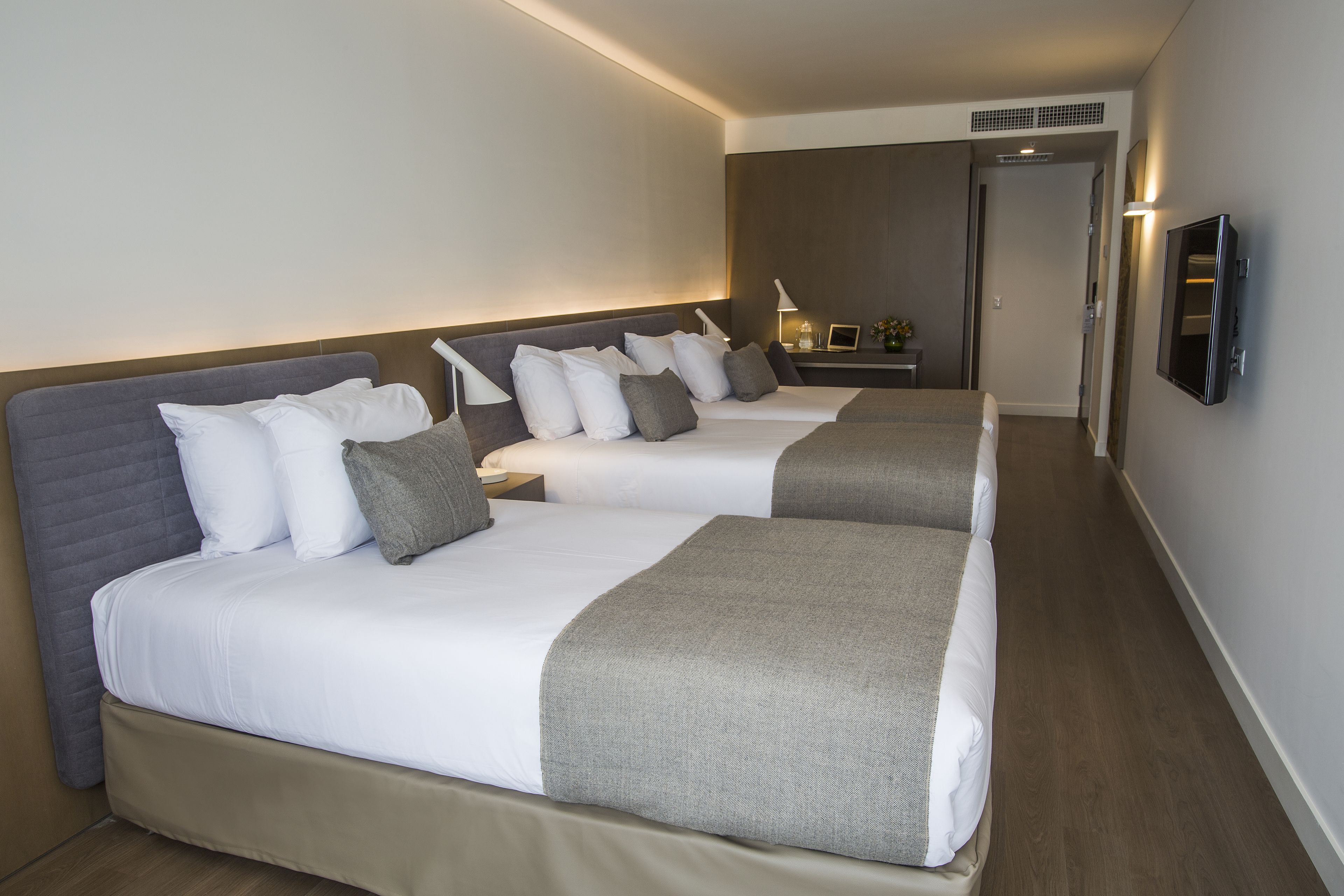 Une chambre d’hôtel avec deux lits, une télévision, un bureau et une lampe.