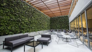 Un patio intérieur agrémenté d’un mur végétal, de sièges et d’une structure de plafond en bois.