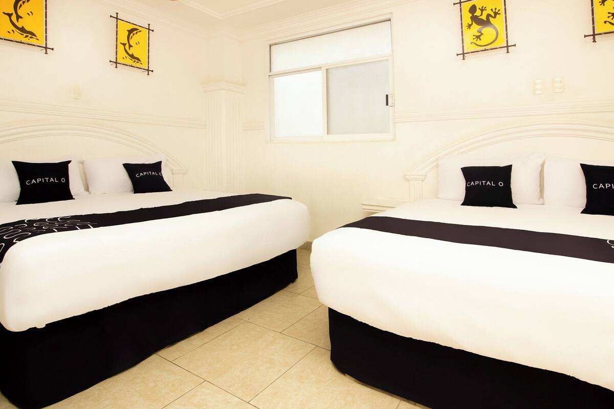 Una habitación de hotel con dos camas, cada una con ropa y almohadas en blanco y negro con la etiqueta 'CAPITAL O'.