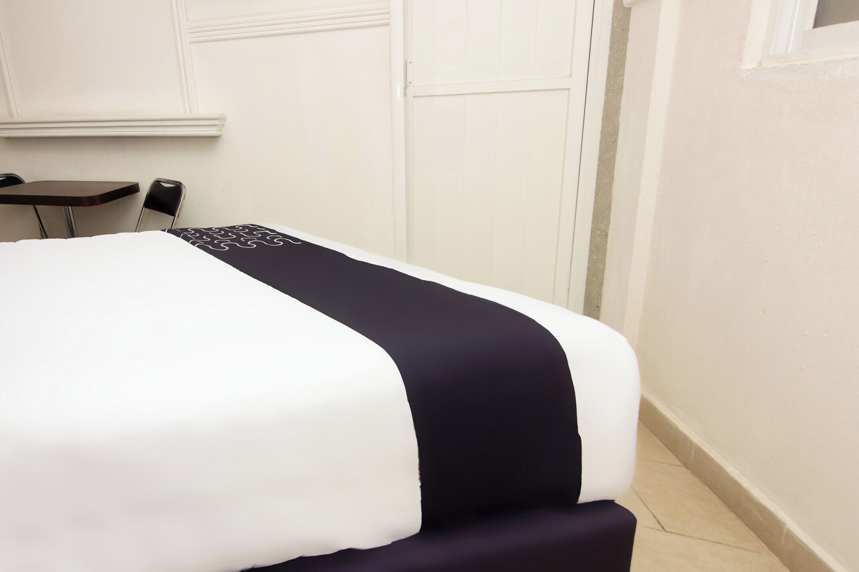 Una habitación de hotel con una cama, una mesita y una silla.