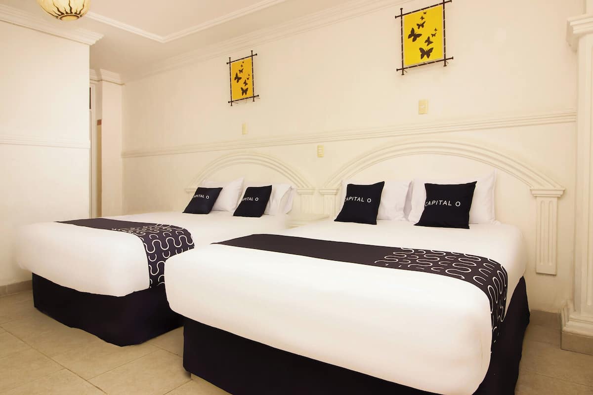 Dos camas con ropa de cama blanca y negra, un cabecero blanco y una decoración de mariposa amarilla en la pared.