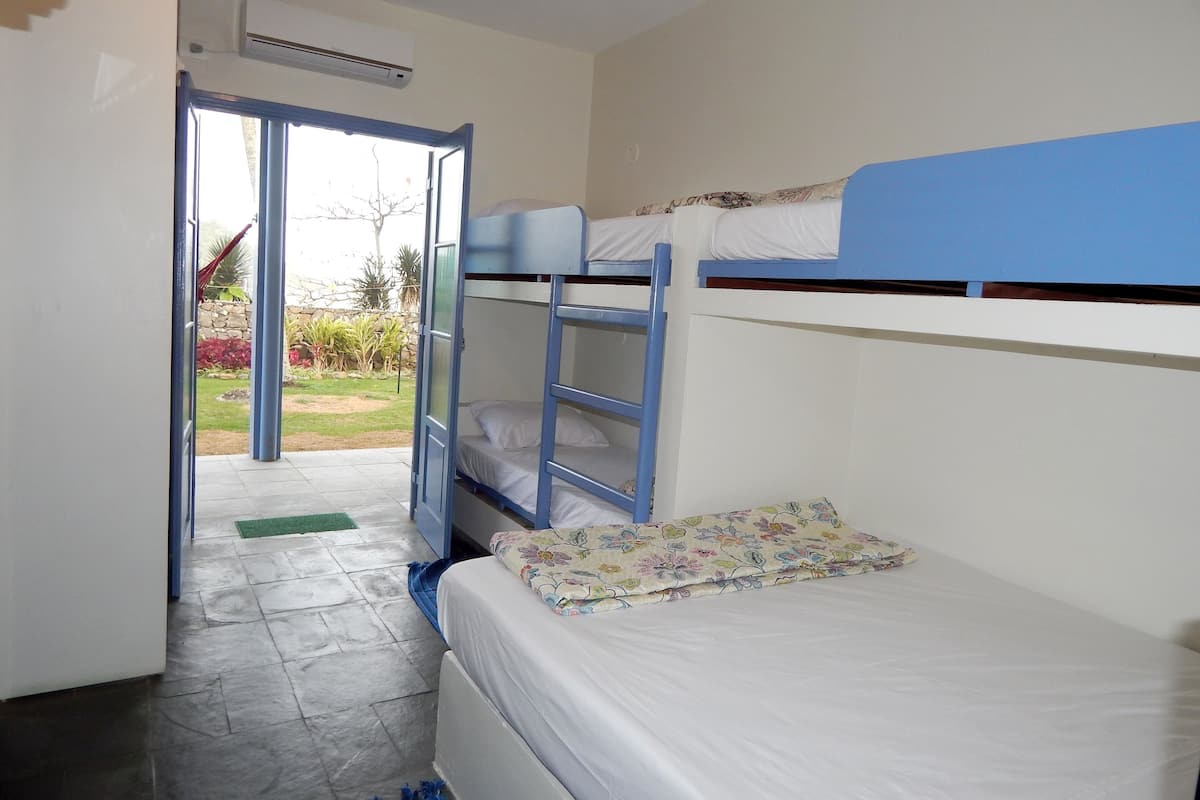 A room with bunk beds, a door leading to an outdoor area, and an air conditioning unit on the wall.