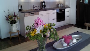 Eine moderne Küche mit weißen Schränken, einer Kaffeemaschine und einem Blumenstrauß auf der Arbeitsplatte.