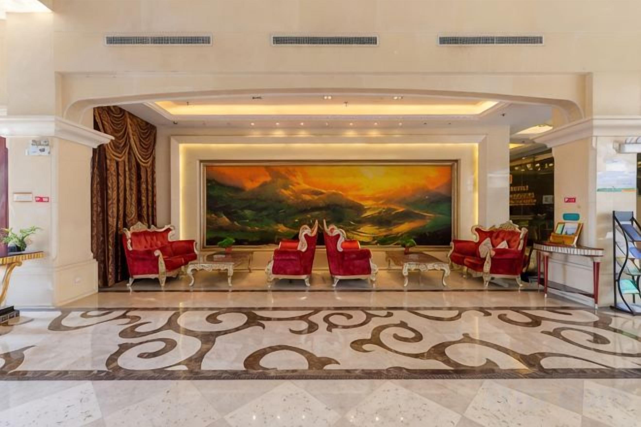 A lobby with a large painting, red seating, and a patterned floor.