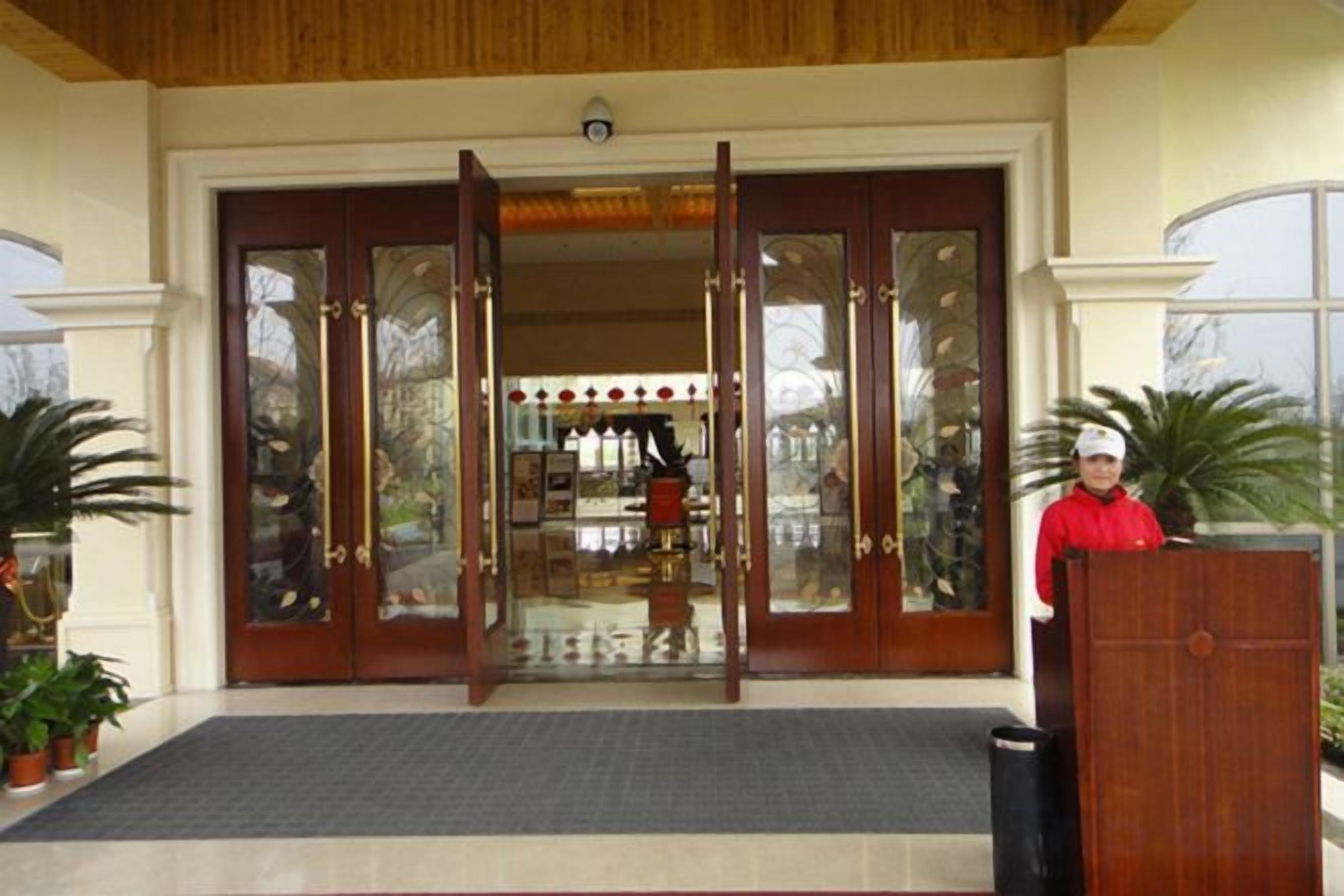 A hotel entrance with a double door, a reception desk, and a mat in front.