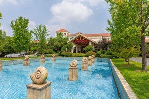 A swimming pool with decorative shells, a building with a red roof, and surrounding greenery.